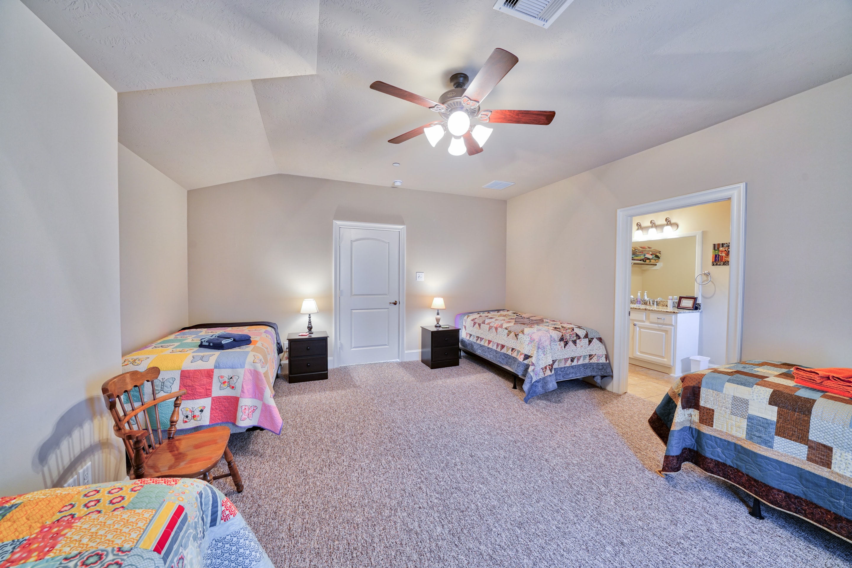 Spacious bedroom with three twin beds and colorful quilts