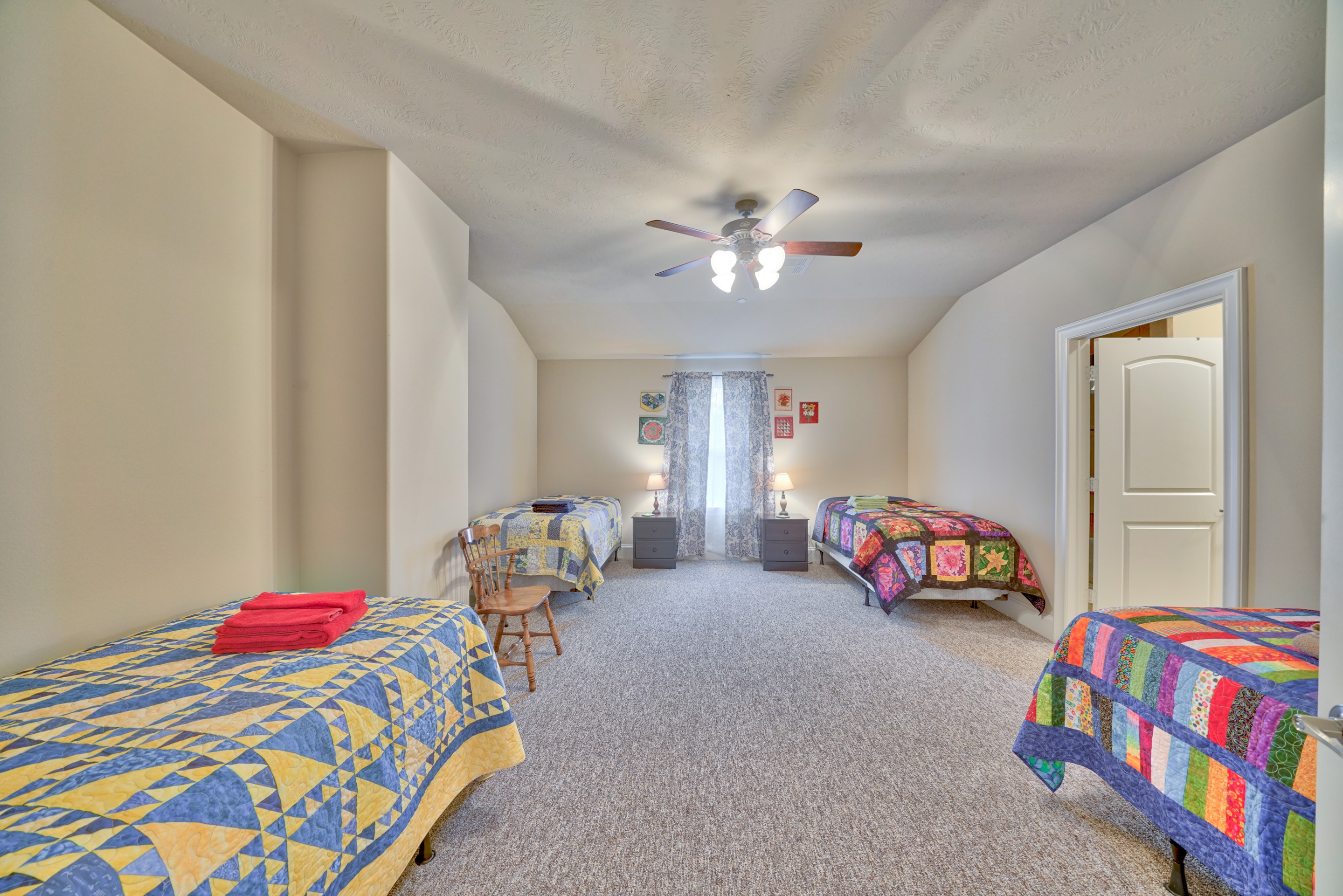 Bright bedroom with multiple twin beds and colorful quilts