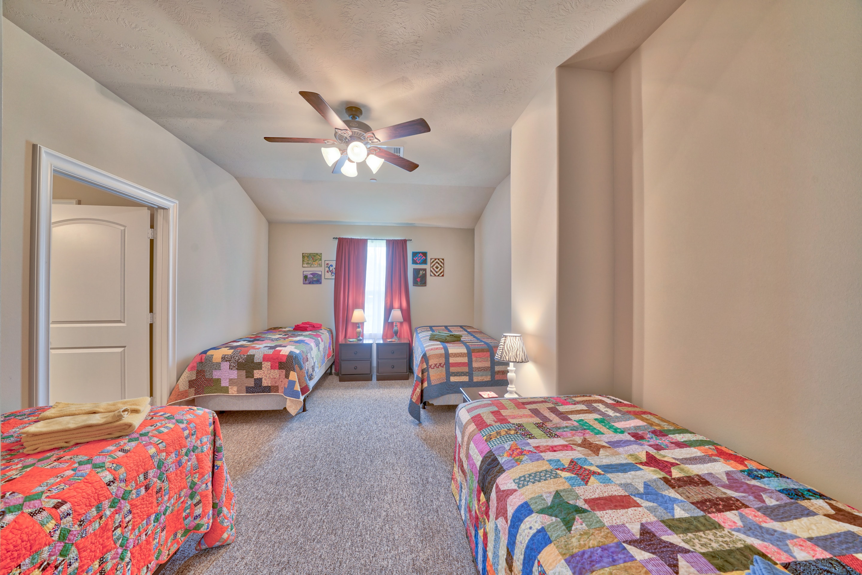 Bedroom with twin beds, pink curtains, and ceiling fan