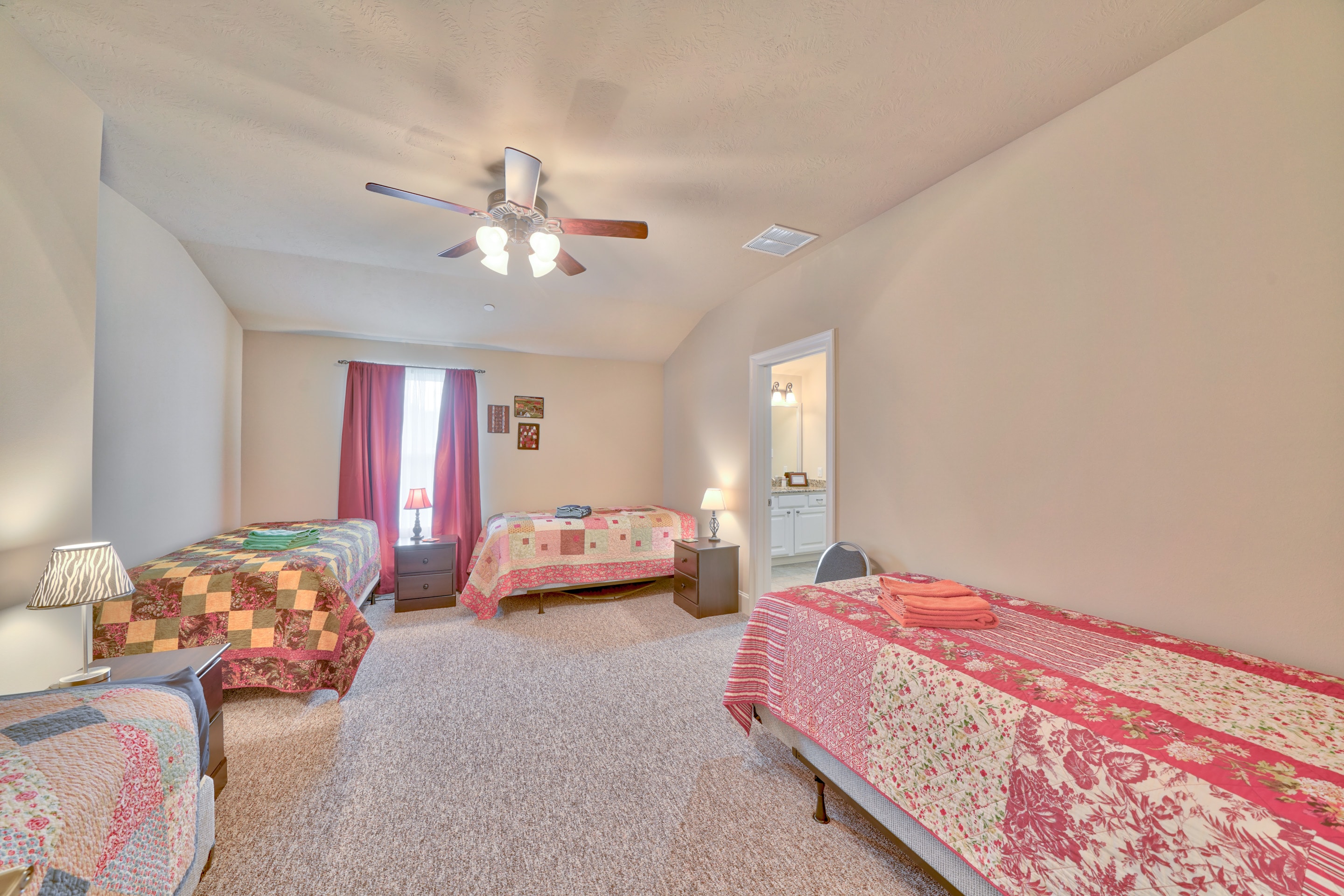 Bedroom with twin beds, pink and coral bedding, and ceiling fan