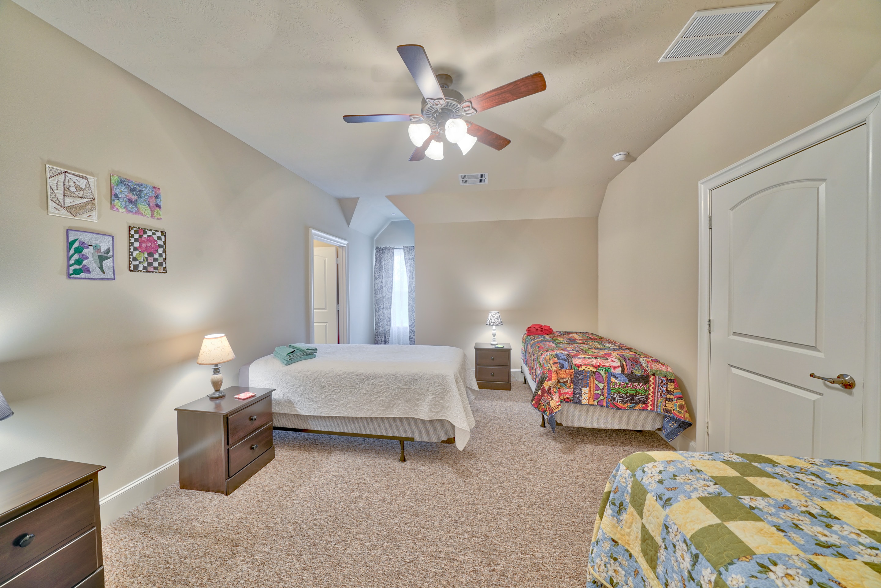 Bedroom with two beds, quilt wall art, and arched doorway