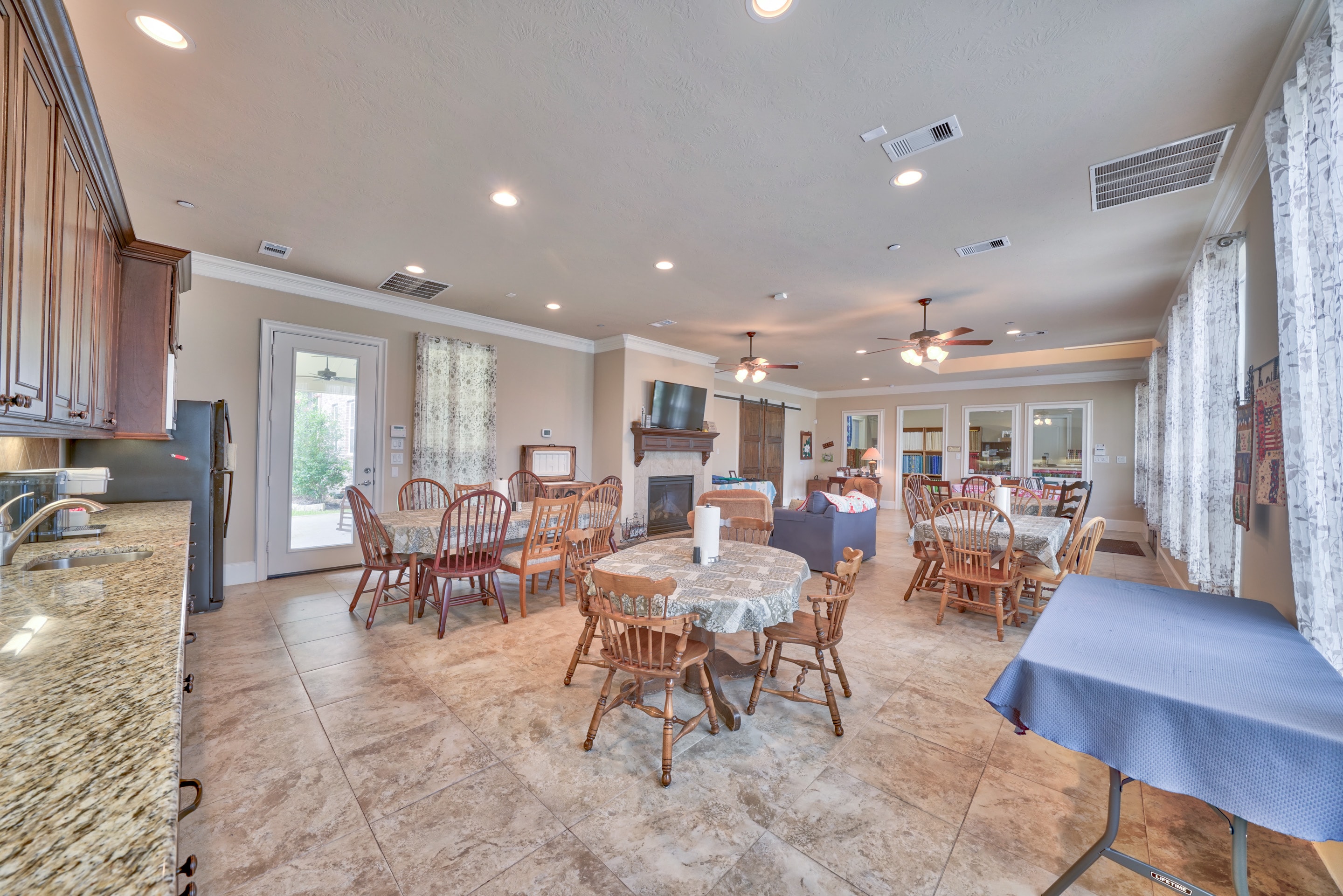 Open dining and sitting area with ceiling fans, fireplace, and large windows