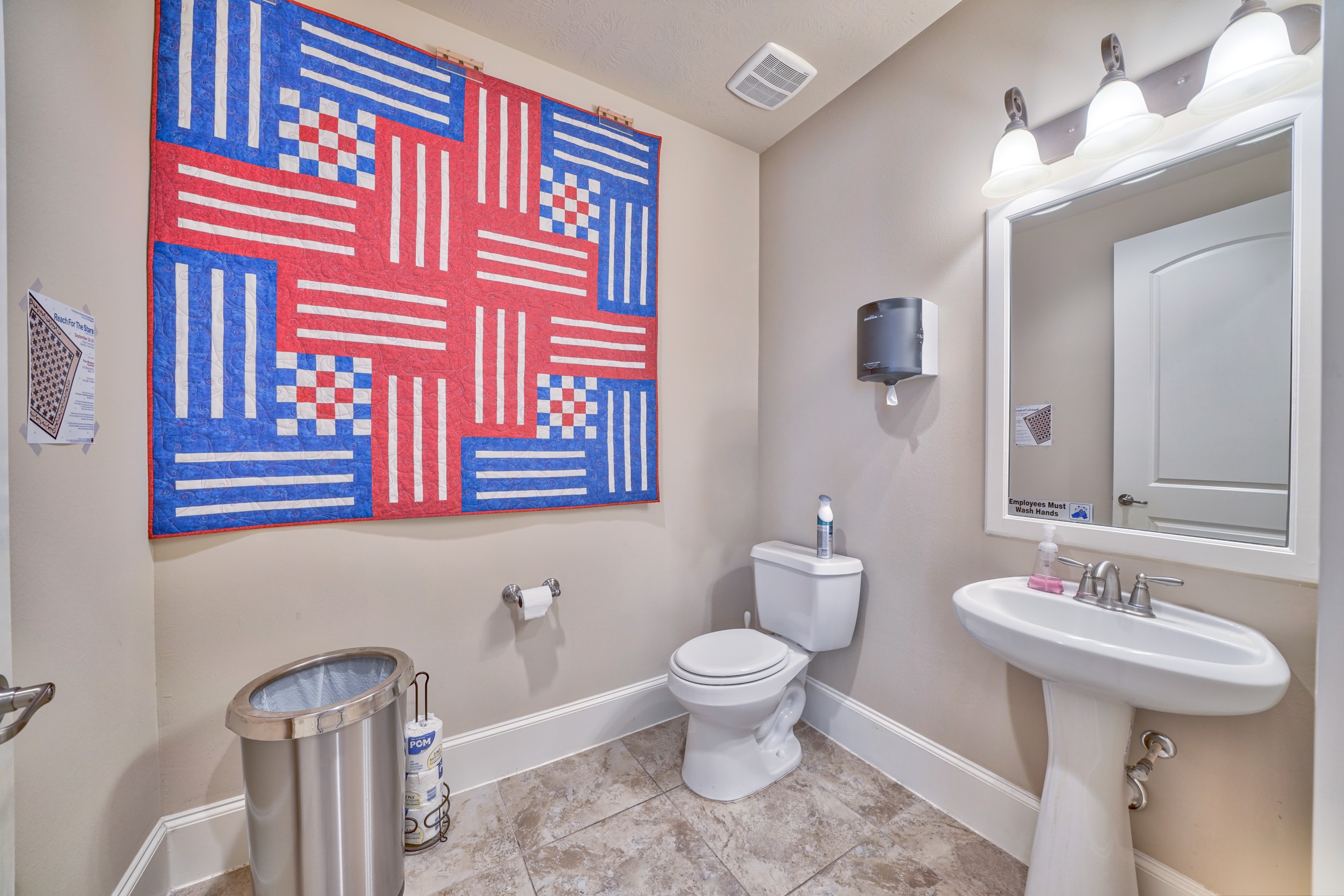 Downstairs bathroom with pedestal sink, quilt wall art, and tile flooring