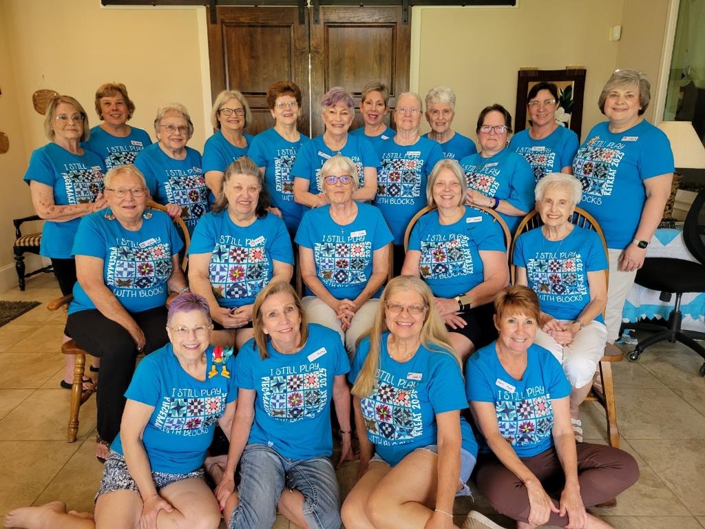 Group of women wearing matching blue Piecemakers Retreat t-shirts gathered at Magnolia Manor