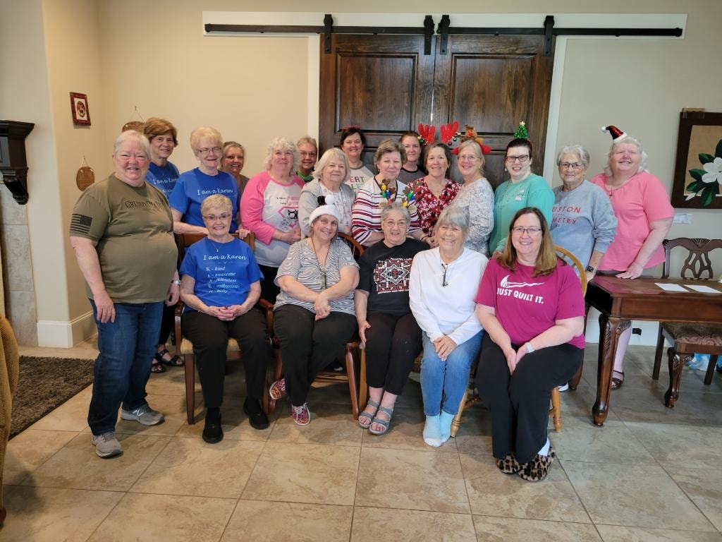 Large group of women in holiday attire gathered in the dining area for a quilting retreat