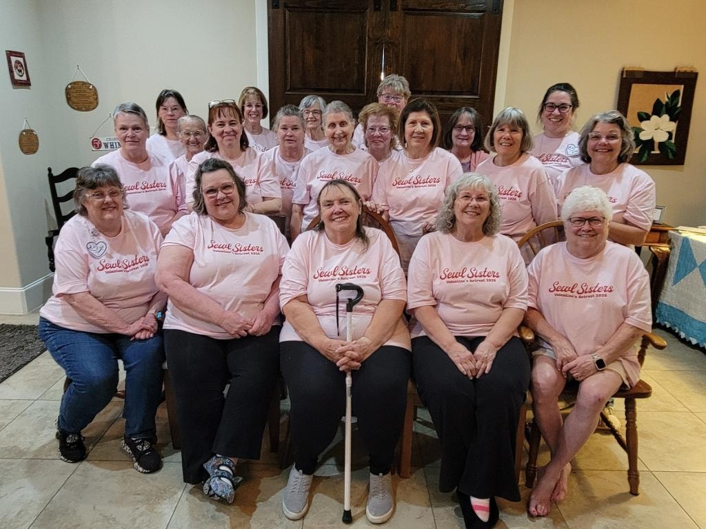 Group of women wearing matching pink Sewl Sisters Valentine's Retreat t-shirts