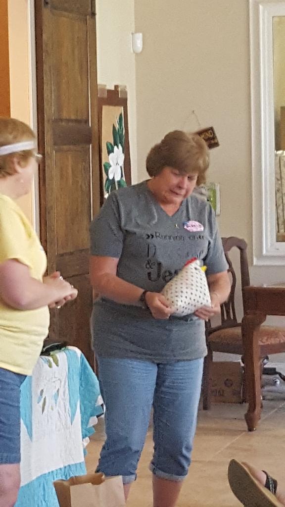 Guest proudly showing off a handmade fabric chicken craft project in the sitting area