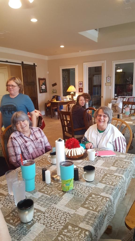 Guests relaxing and enjoying a bundt cake together in the open dining area at Magnolia Manor