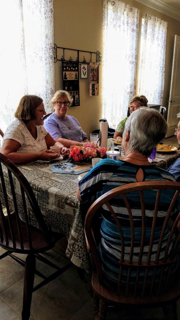 Women gathered around the dining table with a pink flower centerpiece during a retreat meal