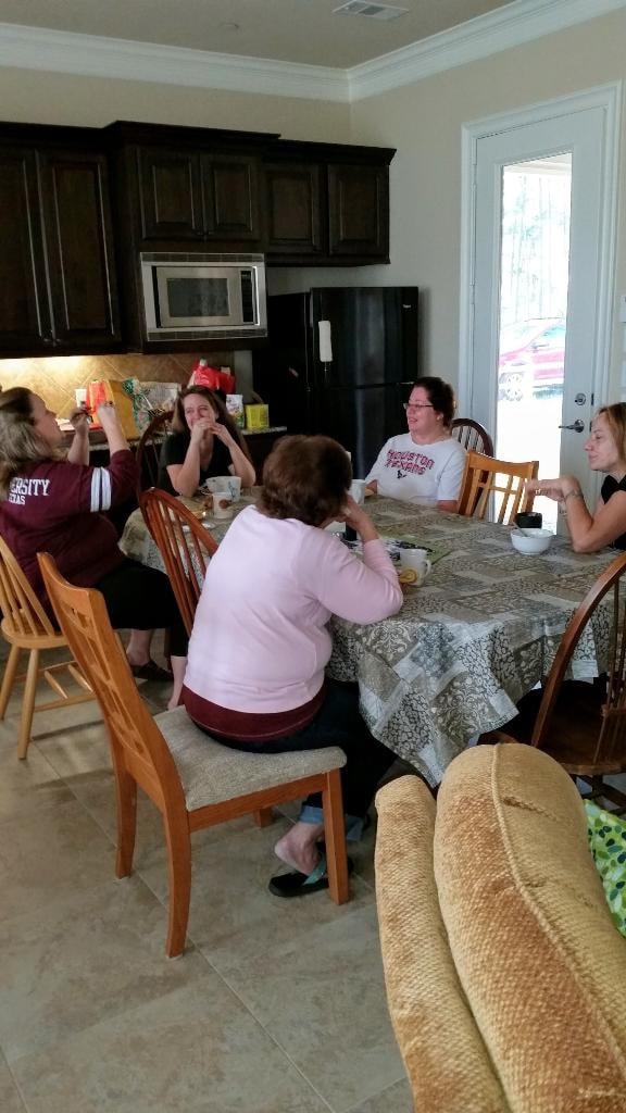 Group of women laughing and chatting together around the kitchen table during a retreat
