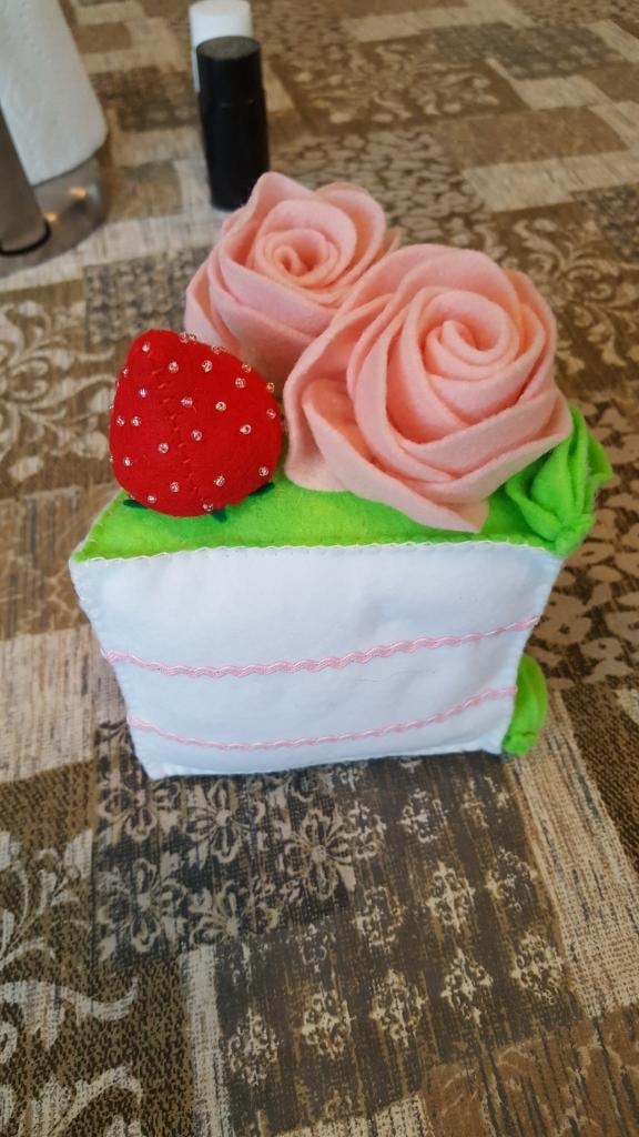 Beautifully crafted felt cake with pink roses and a strawberry made by a retreat guest