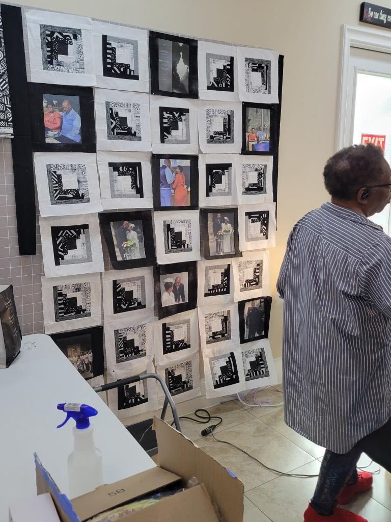 Guest admiring a large black and white photo memory quilt displayed on the design wall, featuring family portraits framed in patterned quilt blocks