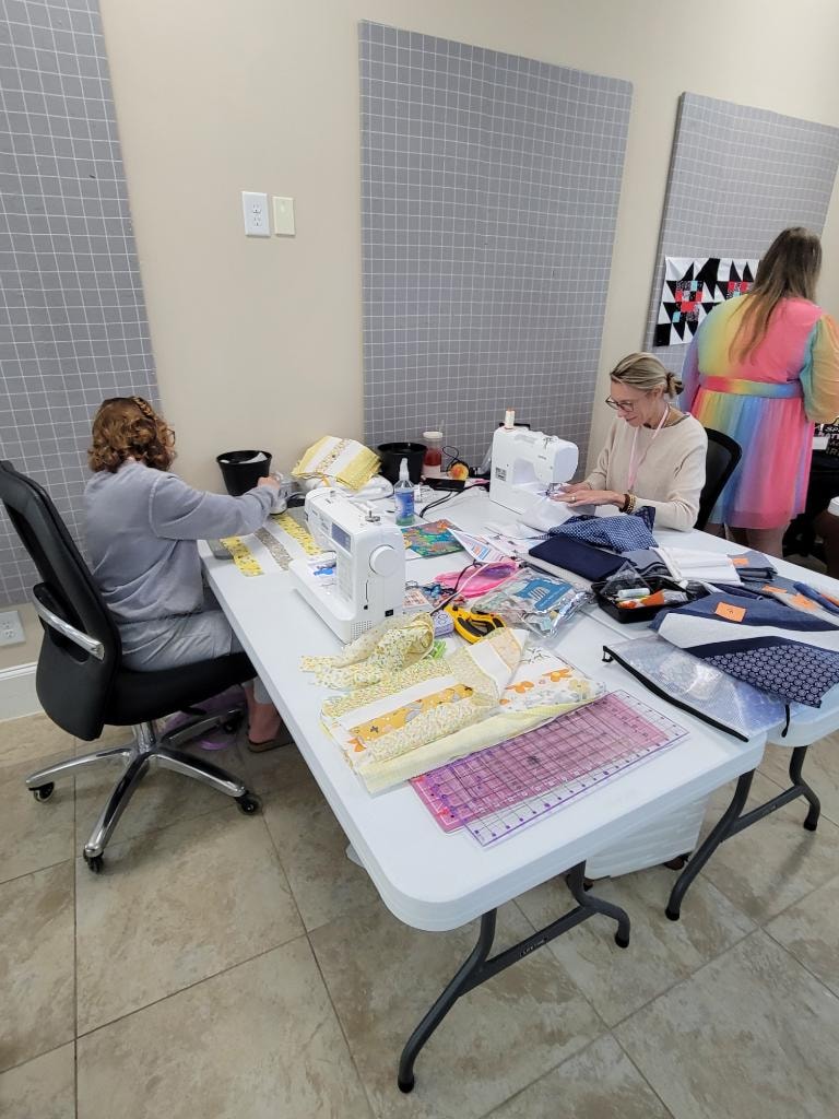 Quilters working at sewing machines in the 1,600 sq ft workroom at Magnolia Manor